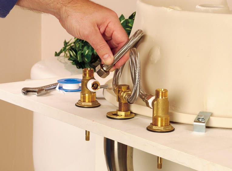 Man connecting the faucet valves to the faucet body, using flexible tubing.