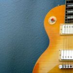 Electric guitar leaning against a blue wall.