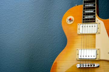 Electric guitar leaning against a blue wall.