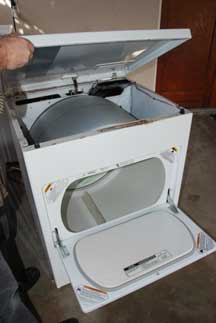 Man’s hand lifting a white clothes dryer's top cover.