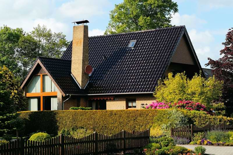 A hedge wrapping around the front of a rural home.