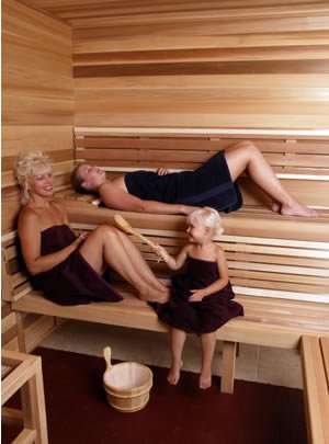 Two women and a child inside a 2-level bench precut sauna kit.