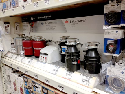 Various types of garbage disposals on a retail display rack.