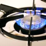 A gas burner's cooktop emitting a blue flame.