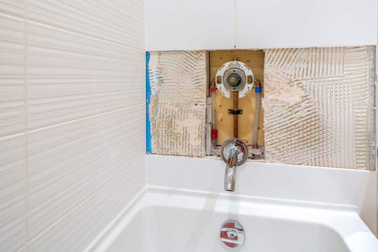 Installation of a diverter valve behind the sidewall of a bathtub.