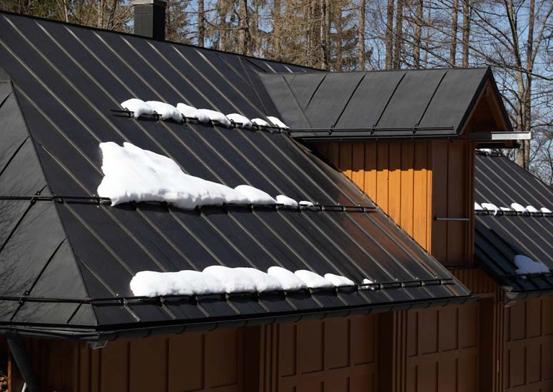 A black sheet metal roof with lines of snow.