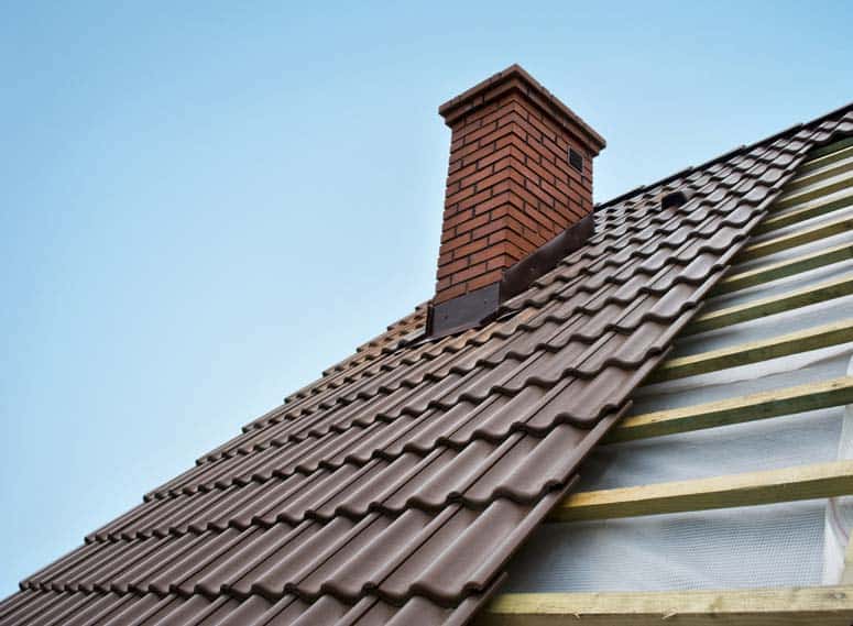 Brown metal shingles roofing over wooden battens including a brick chimney.