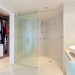 A bathroom’s built-in shower area separated by a top-hung glass sliding door.