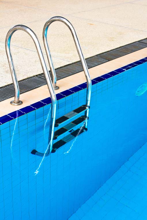 swimming pool ladder mounted at edge of pool