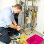 A technician using diagnostic tools on a home furnace in the basement.