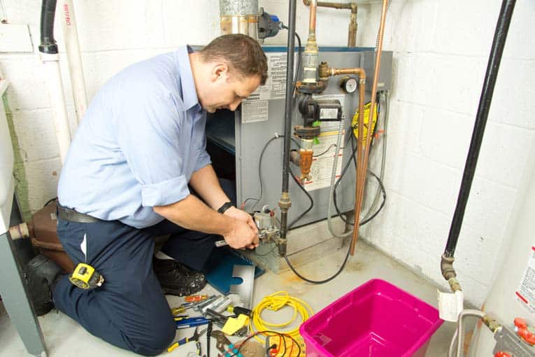 A technician using diagnostic tools on a home furnace in the basement.