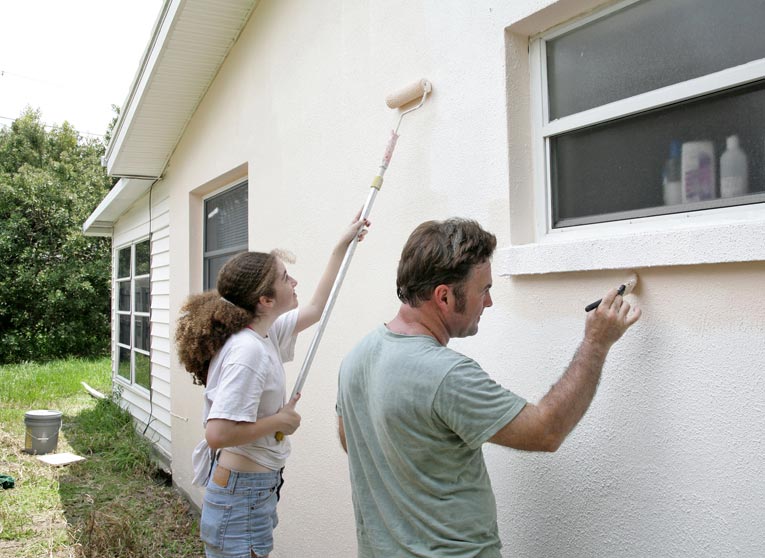 painting house with roller and brush