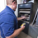 Technician in a blue shirt working on an open furnace