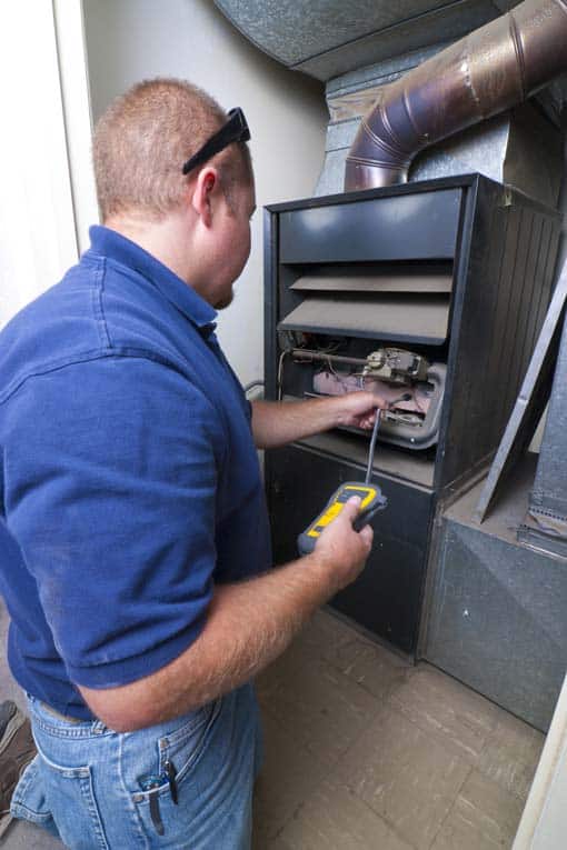 Technician in a blue shirt working on an open furnace