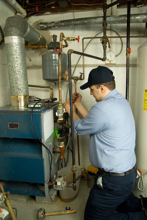 Technician using tools on a home furnace in the basement