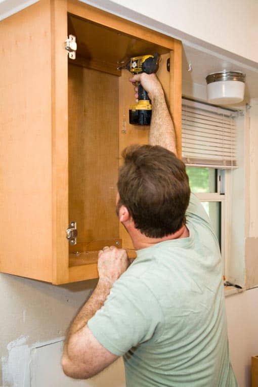 Screw through structural parts of the cabinet back into wall studs for solid support.