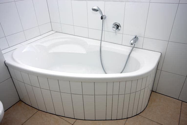 Small corner bathtub is designed to squeeze into a corner in a small bathroom.