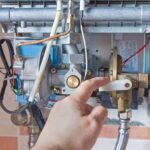 Man's finger pulling down a lever on a bare tankless water heater.