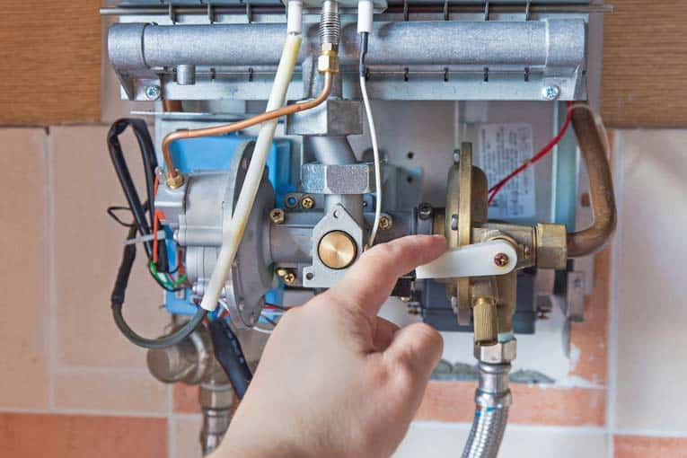 Man's finger pulling down a lever on a bare tankless water heater.