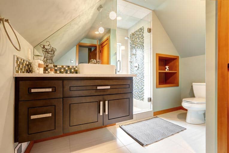 Custom cabinets wedge into an angled nook in this attic bathroom, making maximum use of the available space.