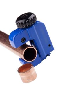 A small blue tubing cutter on a copper pipe with a cutting.