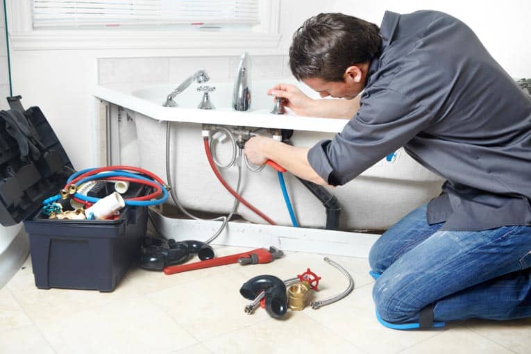 Man installing water supply lines to bathtub valves.