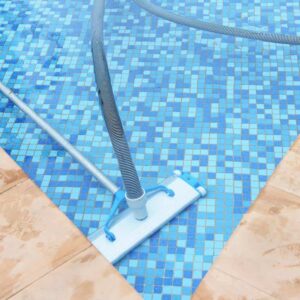 A pool vacuum has a hose that hooks up to the pool's intake. You guide it along the bottom and sides with an extension pole.