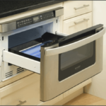 An opened microwave oven drawer below a kitchen countertop.