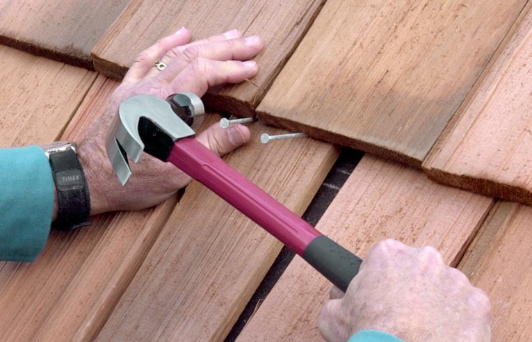 Fasten the shingle with two roofing nails, angled upward. Then tap the shingle up into place.