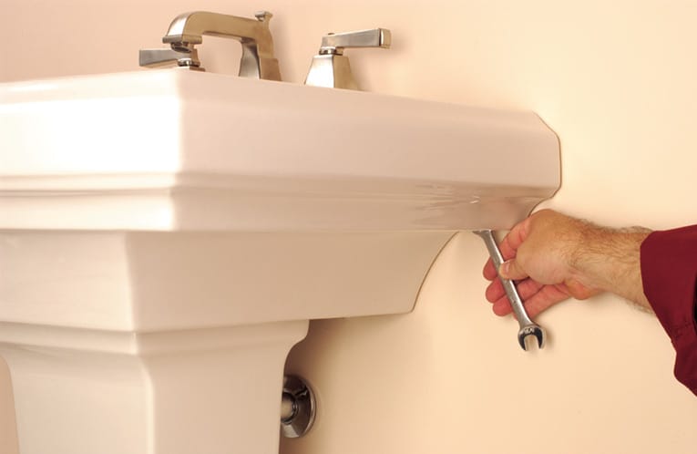 Fasten the sink to the wall, using a wrench.