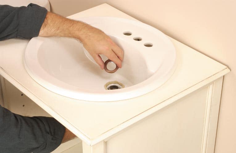 Man sealing the drain assembly and tail piece.