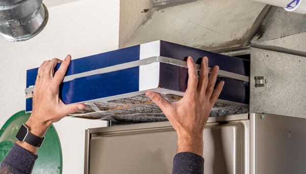 Man's hands changing a furnace filter.