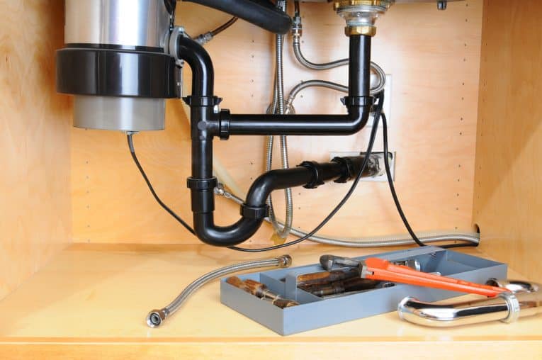 Kitchen plumbing system beneath a sink, including disposer and joined piping.