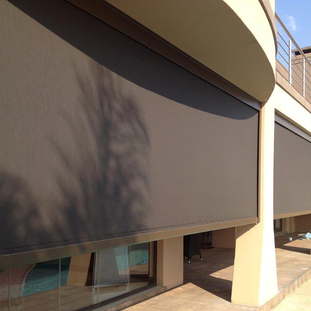 A large exterior solar screen shade with side channel mounts.