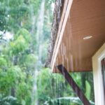 Rain falling on a roof, over a house’s eaves.