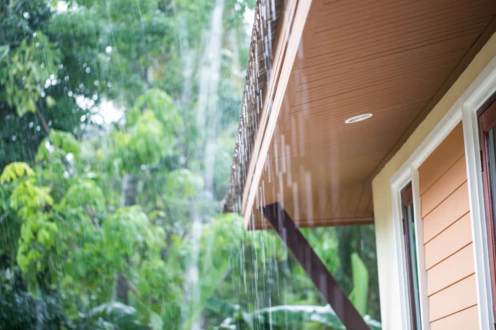 Rain falling on a roof, over a house’s eaves.