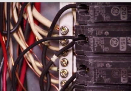 Circuit breakers with black wires attached including screwed white and copper wires.