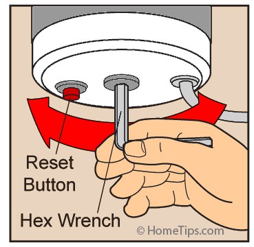 A hand using a hex wrench to manually rotate clogged garbage disposal impellers.