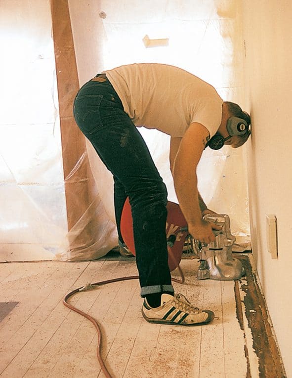 Man sanding a worn-out hardwood floor.