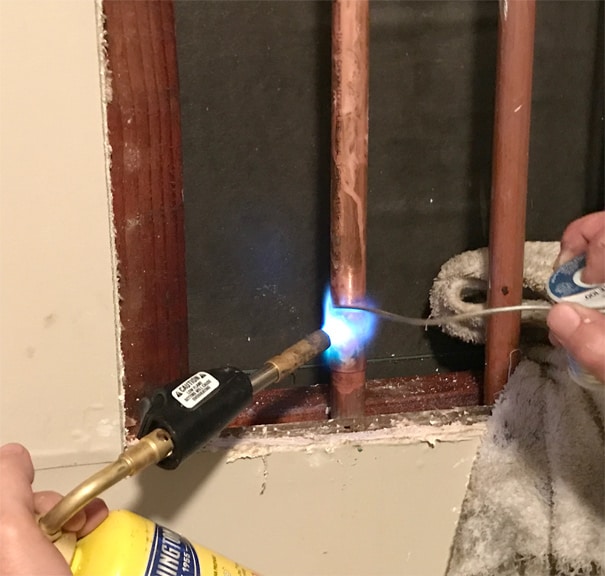 Man’s hands soldering a bottom coupling with a Worthington torch kit.