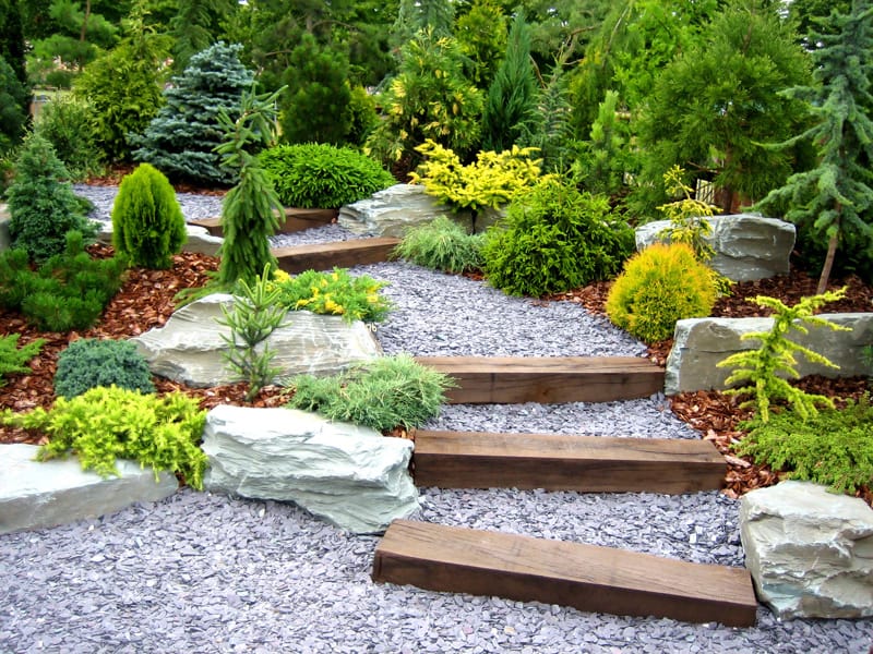 A gently rising pathway of gravel, with large wood beam steps.