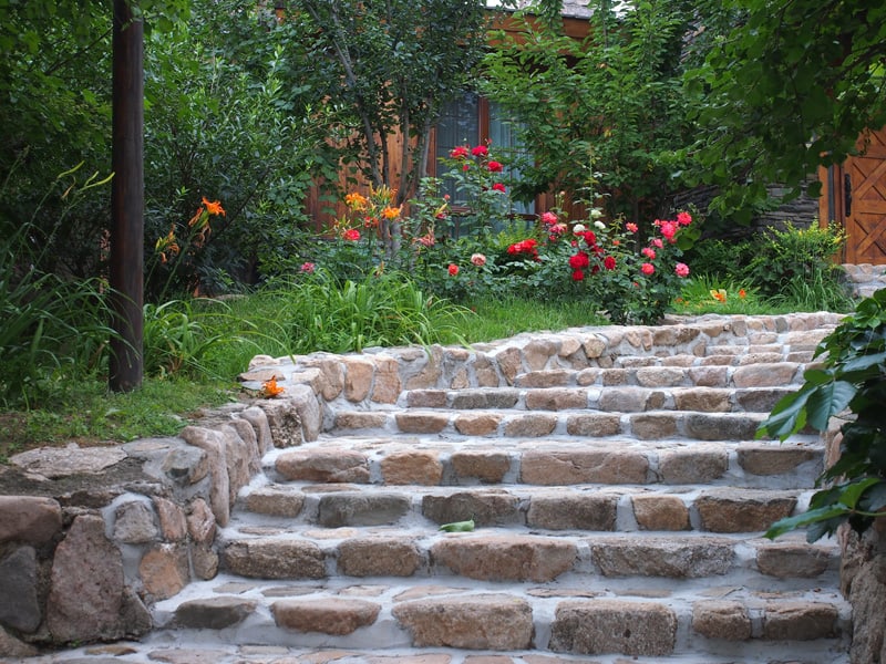 Rose bushes and grass next to garden steps made of rounded retaining stones.