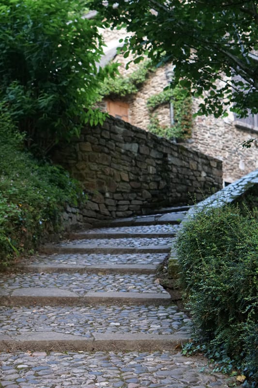 An ascending stone pathway made of cobblestone and concrete beams.