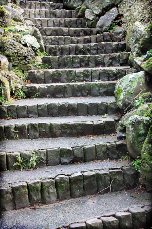 An asian style rock stair case winding up a rocky hillside.