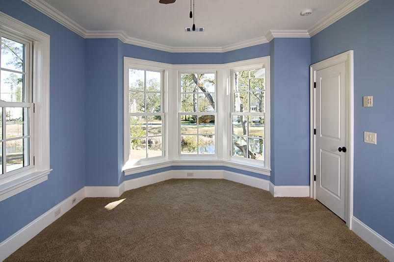 Blue carpeted room with baseboard and crown molding interior trim.