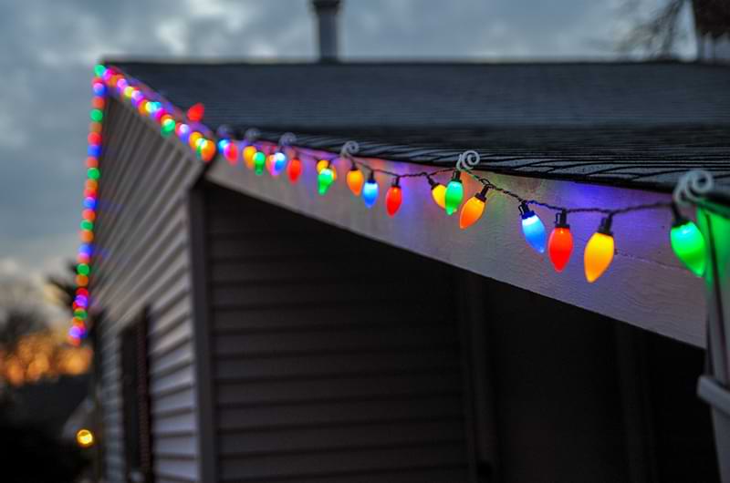 Multi-colored holiday lights on the roof line of a house.