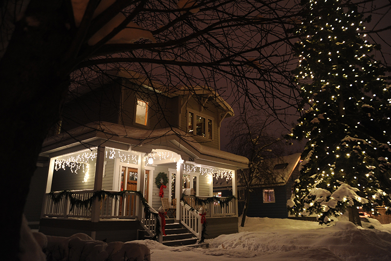 A home with icicle christmas lights and a large christmas tree in the front yard