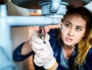 A woman working below a leaking sink