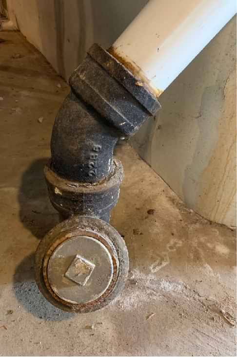 sewer pipe cleanout and elbow on home's plumbing stack