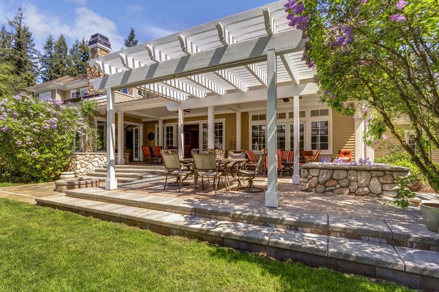 Wooden pergola filters sunlight on patio with this house-attached shade shelter.